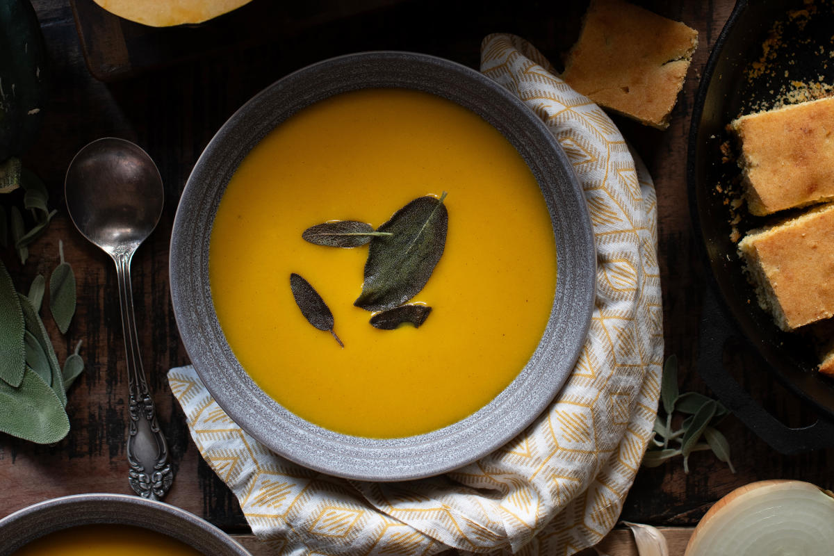 Sweetwater Harvest Kitchen's Vegan Spiced Butternut Squash Soup surrounded by raw ingredients.