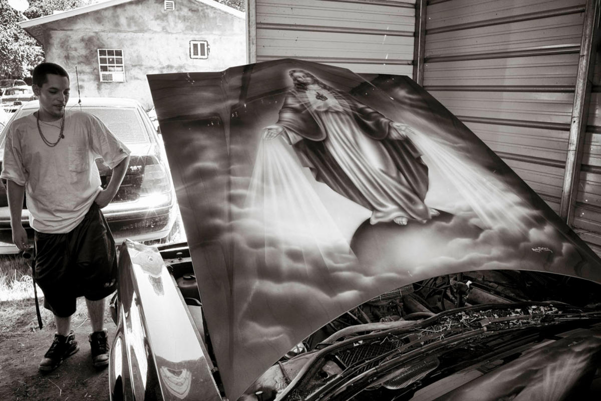 eroy Martinez stands beside his Cadillac lowrider in Chimayó in 2015. The mural on its hood was created by one of Chimayó’s most renowned car muralists, Randy Martinez, in the early 2000s. Lowriders sometimes add religious imagery to their paint jobs, an outgrowth of the centuries-long tradition of religious folk art in northern New Mexico.