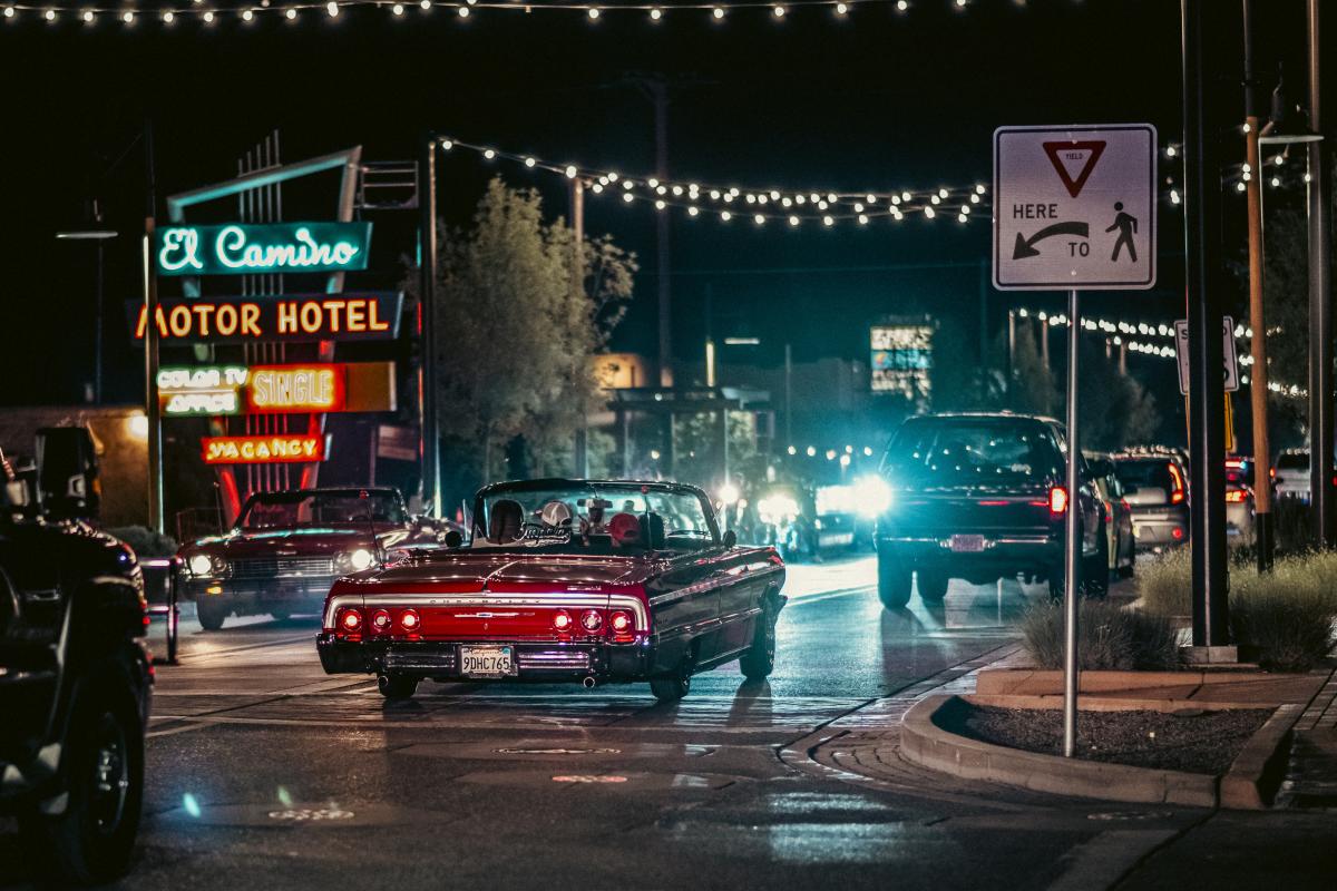 A red Chevrolet Impala drives past the El Camino Motor Hotel sign along Fourth Street in Los Ranchos on a warm September evening.