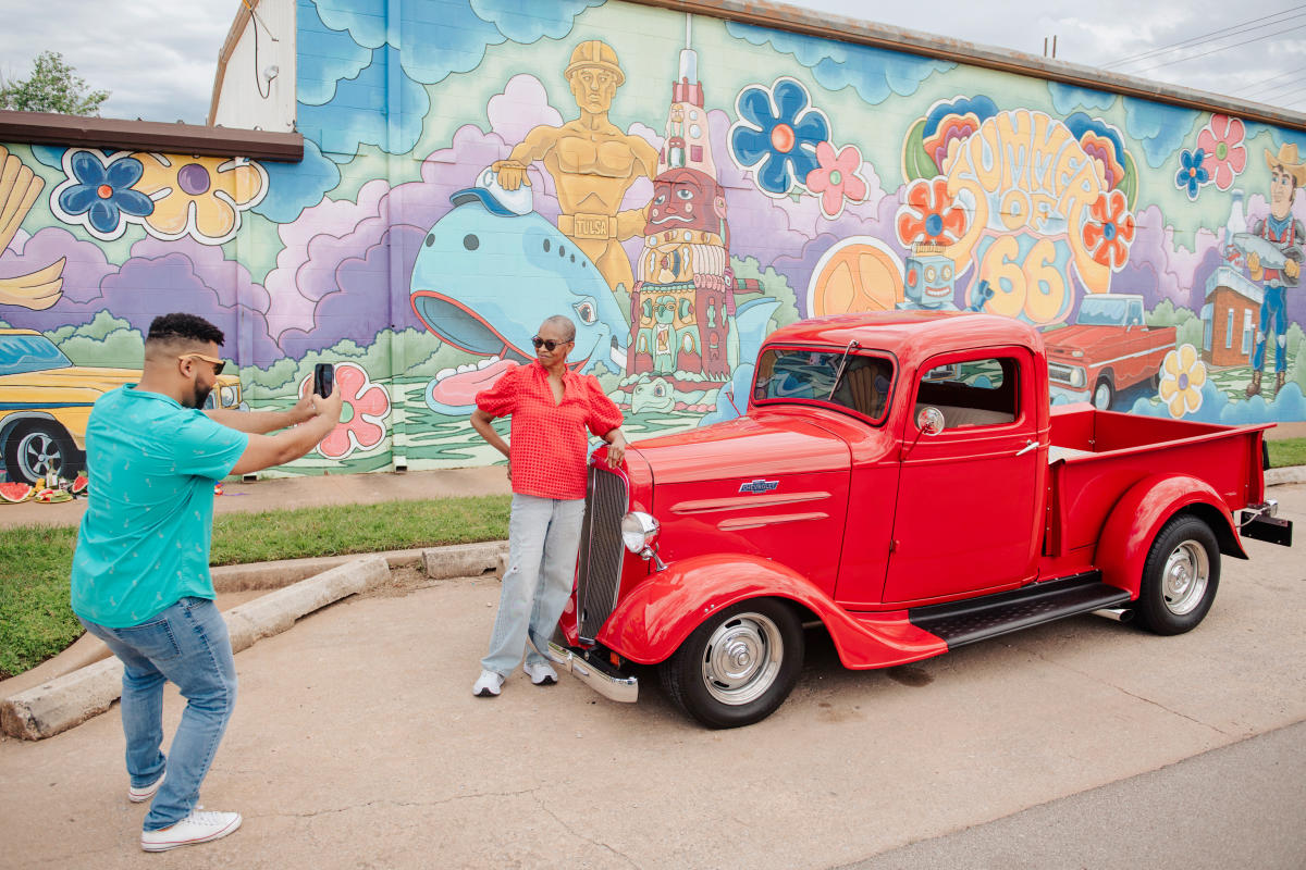 Woman posing with red truck in front of Summer of 66 mural in 39th Street District