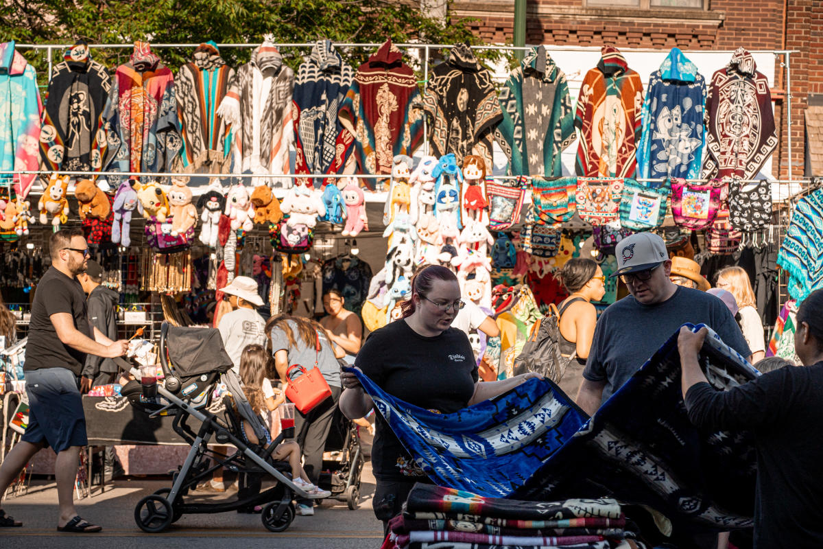 People shopping in the South Omaha neighborhood looking at tapestries.