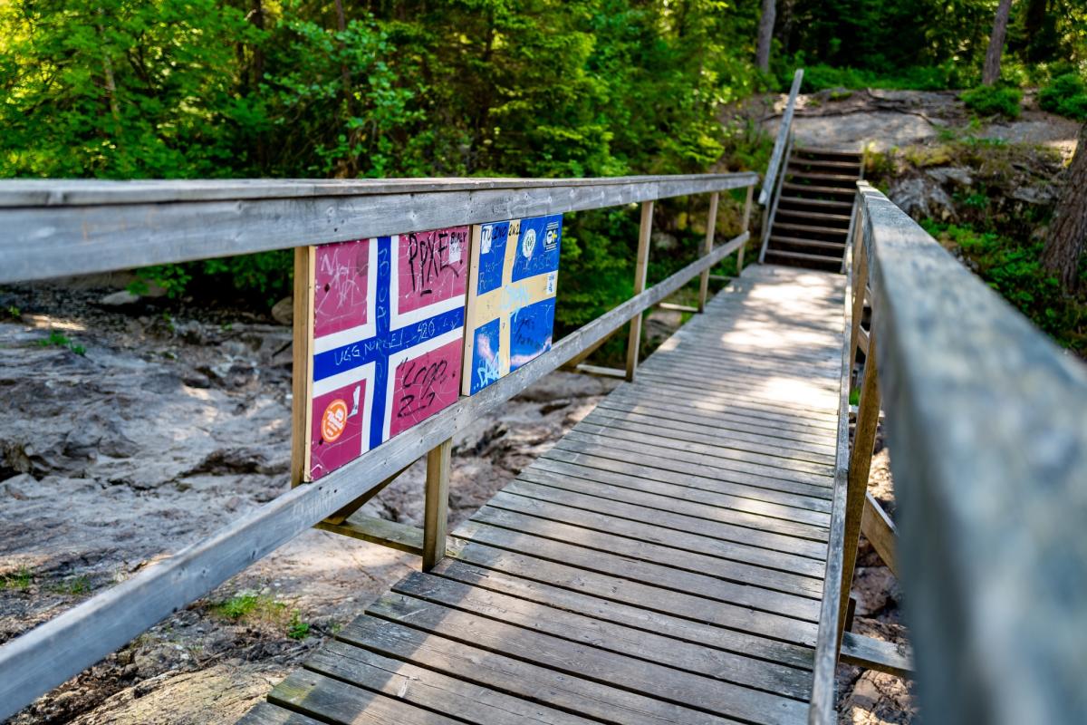 Svenskegrensen på Borgleden. Ei trebro med trapp og med et norsk og et svensk flagg som markerer riksgrensen.