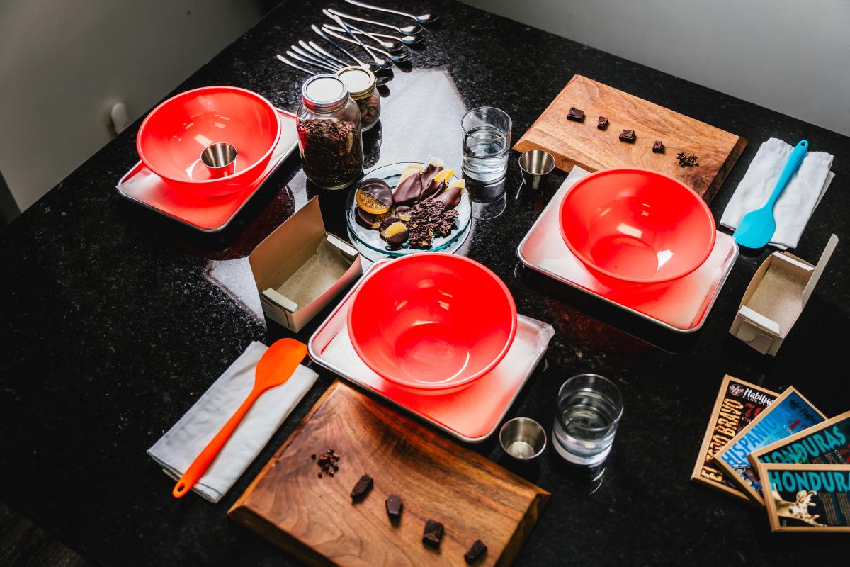 A table set with bowls, boards with chocolate samples, jars and spoons ready for a chocolate making experience