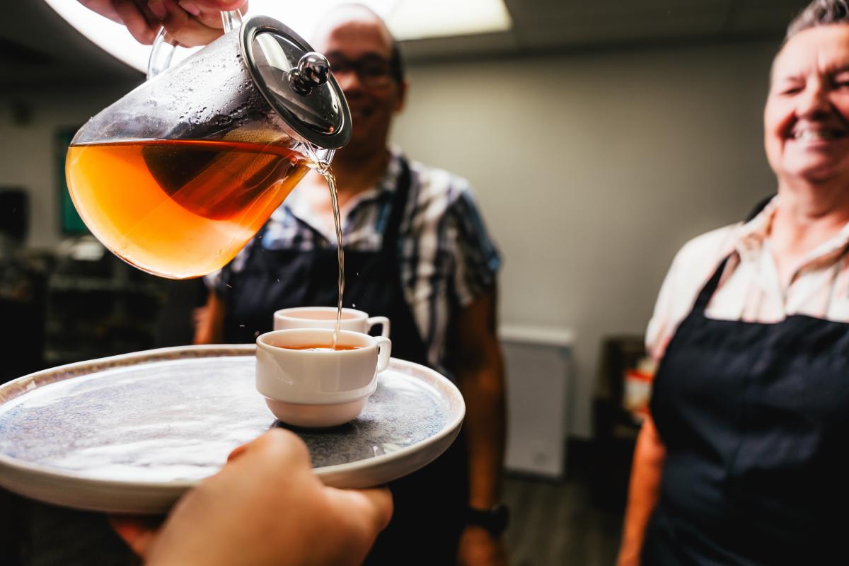 Teapot tipped with tea going in a cup