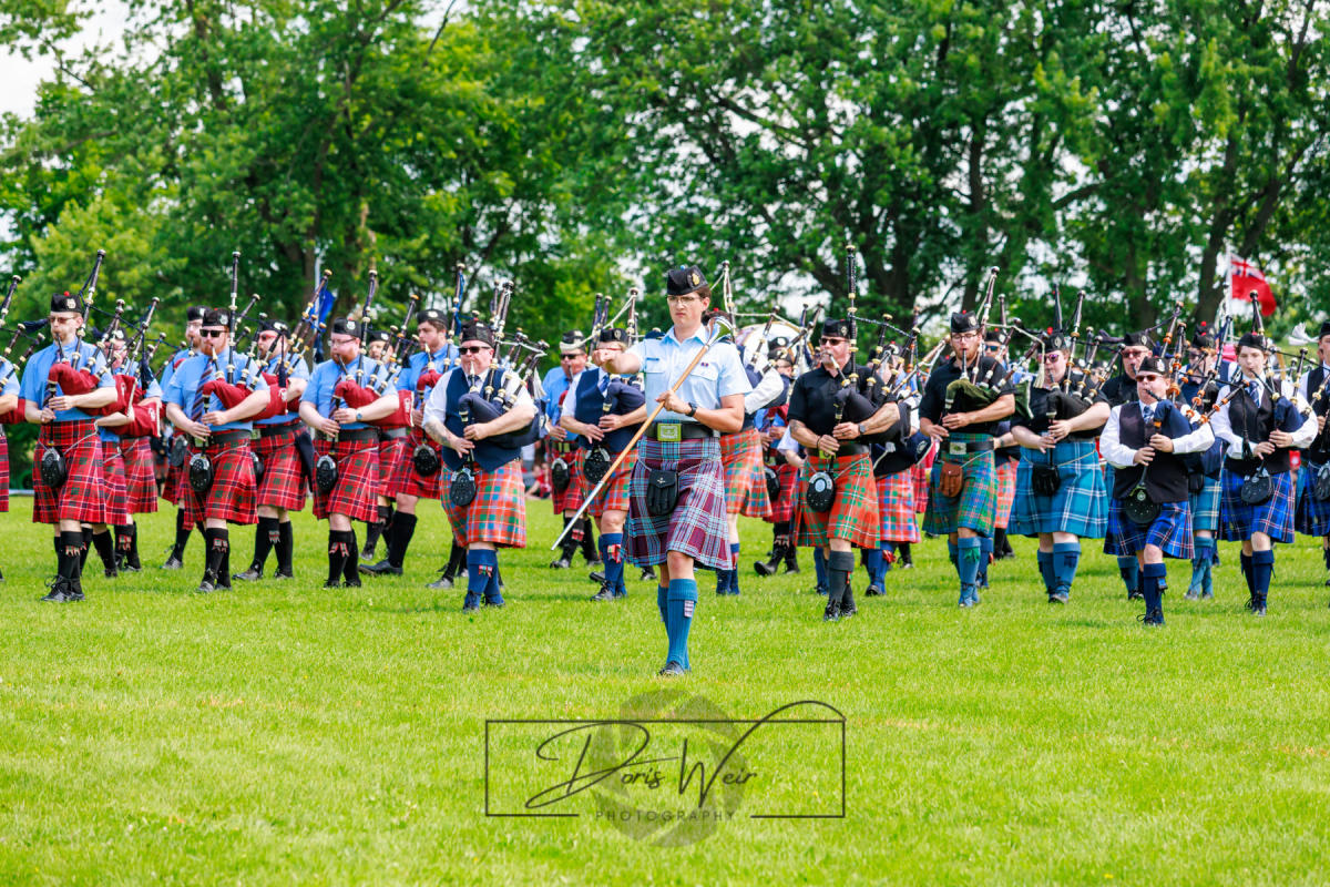 A pipe band in kilts play on bright green grass