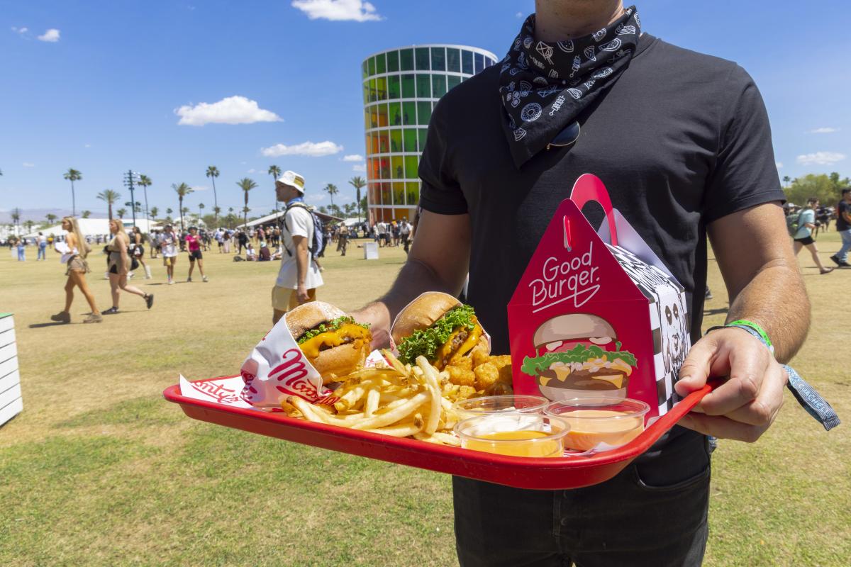 A person holds up a tray of food from Monty's Good Burger while standing in the middle of the Coachella Valley Music and Arts Festival grounds.