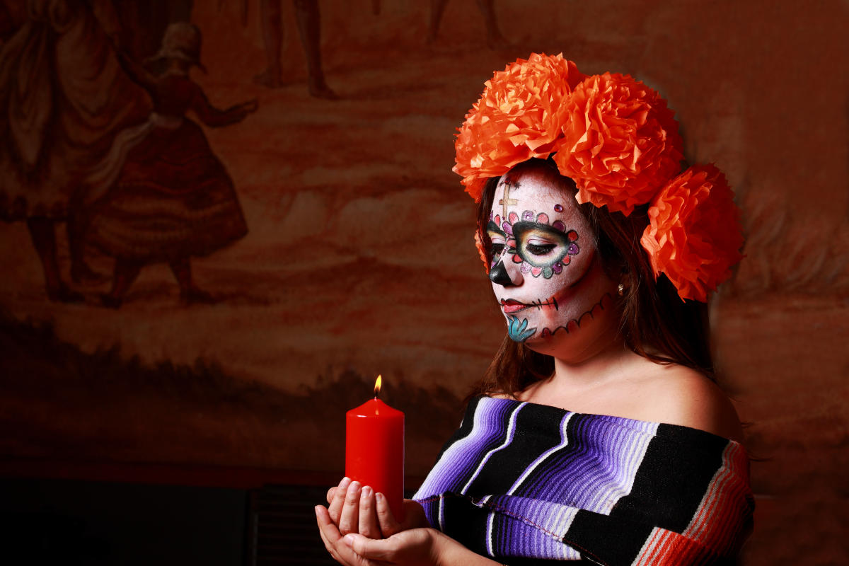 Woman holding a candle in Day of the Dead makeup