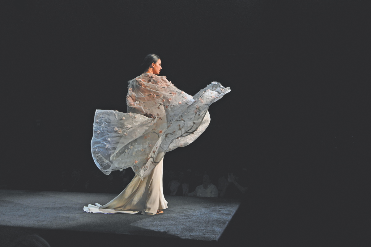 The back of a woman on the runway, her dress billowing behind her.