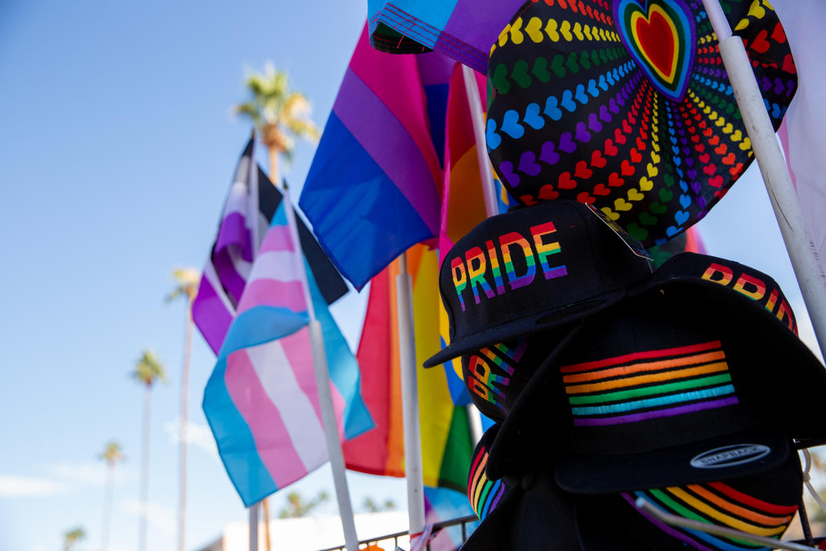 Variety of Pride flags signifying diversity and inclusion waving in the sky with blue skies and mountains