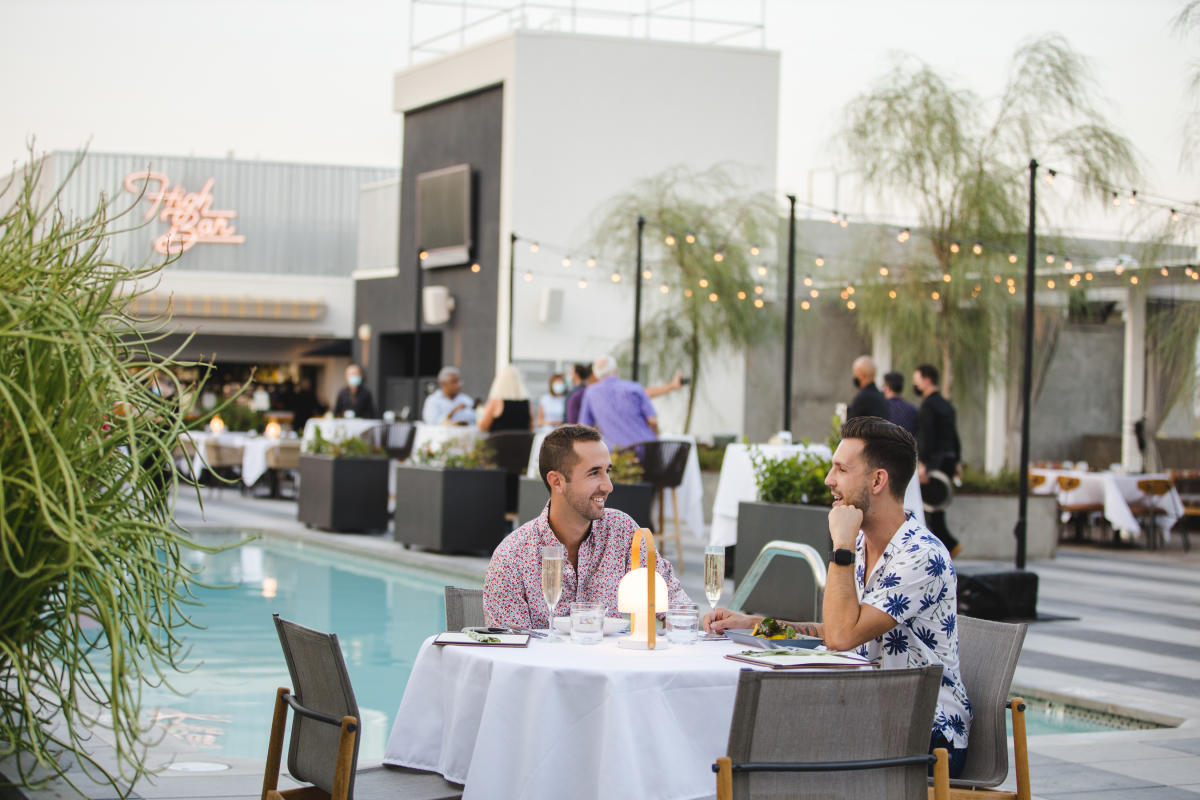 Couple dines on rooftop of the Kimpton Rowan next to the pool.