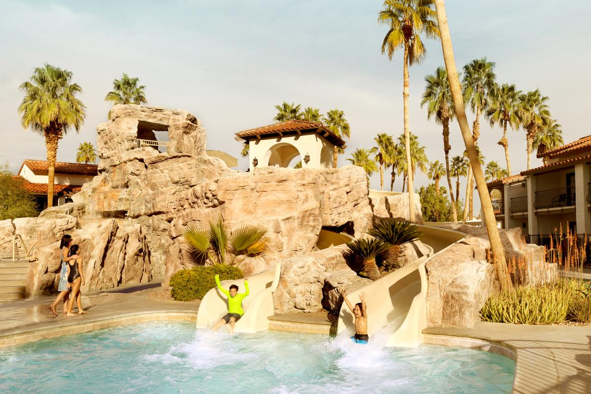 Two people at the bottom of water slides get ready to splash into a pool at Omni Rancho Las Palmas