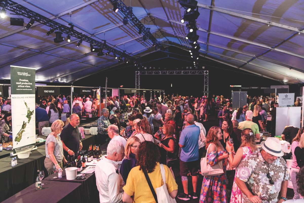 A crowd of people sip wine and eat underneath a huge tent during the Grand Tasting event at the 2023 Palm Desert Food & Wine Festival.