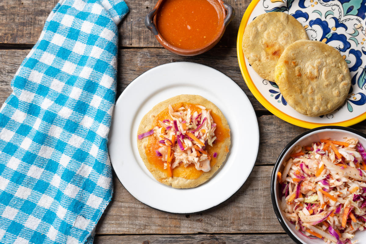 Salvadoran pupusas with coleslaw and tomato sauce on wooden background