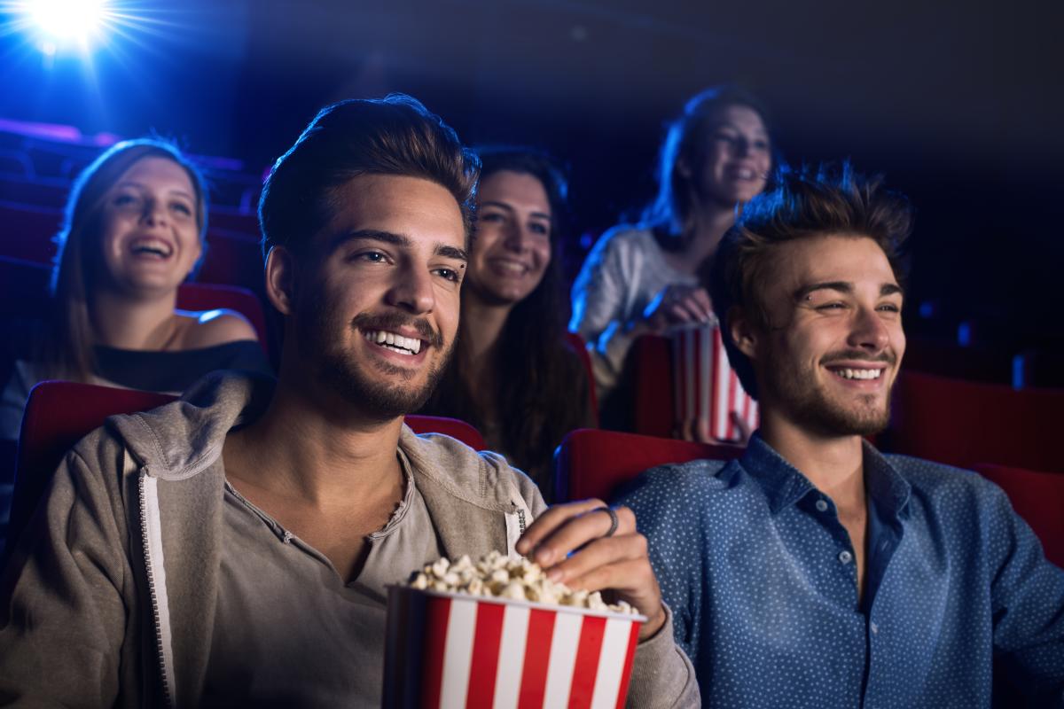 Gay men enjoying popcorn while sitting in a movie theater