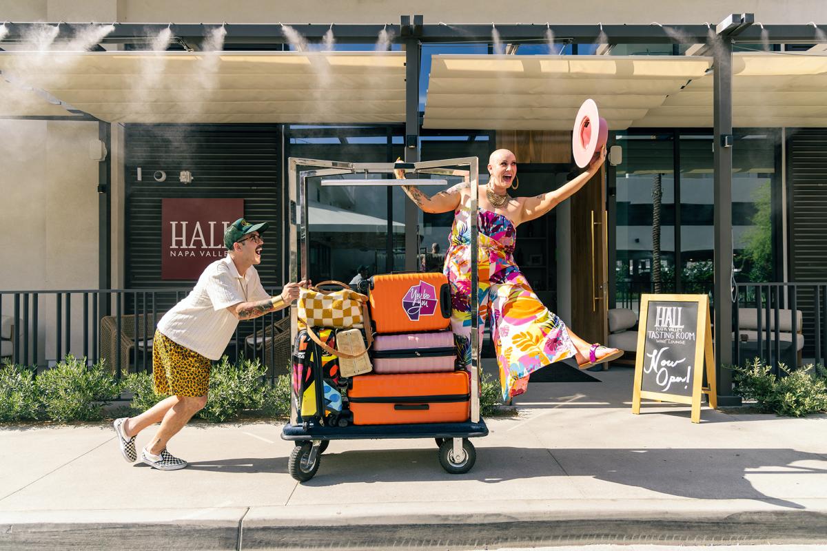 Two people pushing a travel cart in front of the Thompson Hotel in Palm Springs