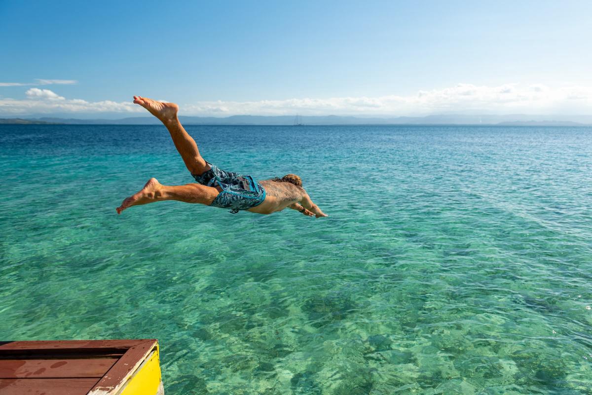 Man Jumps into the water from small pier, Isla Colón, Bocas del Toro
