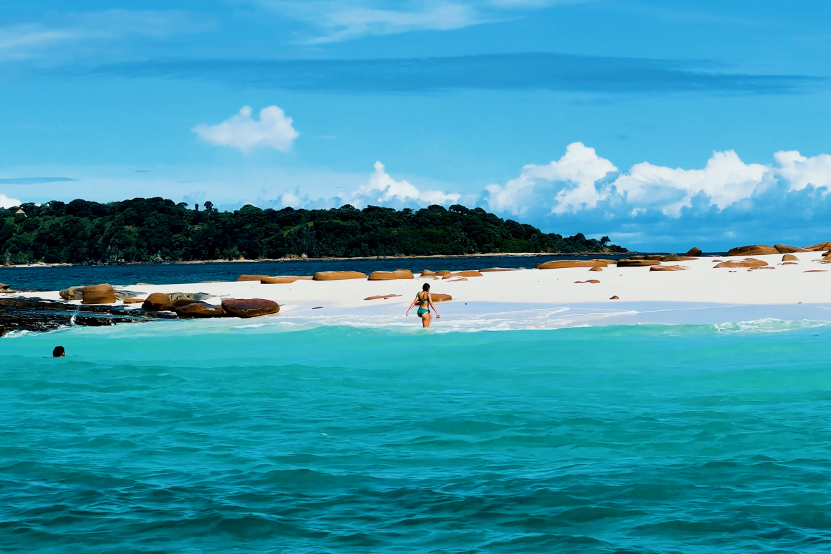 Woman walking along the beautiful sunny beach of Bartolome Island, Pearl Islands Panama City, Panamá