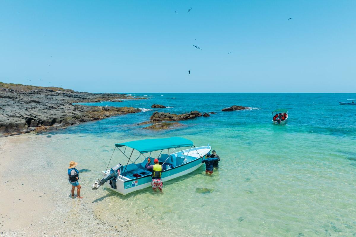 Boat with tourists arriving at Iguana Island in the clear waters of Panama’s Pacific