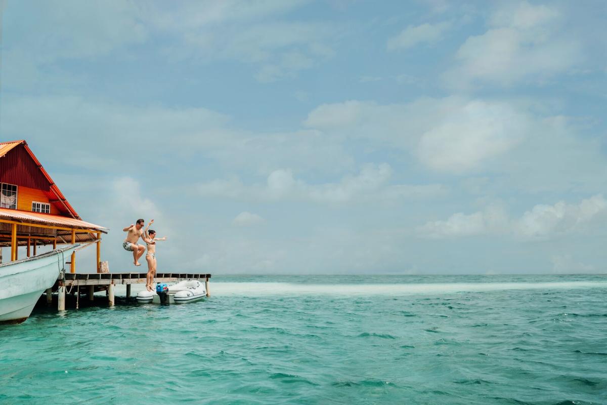 Tourists jumping from a dock in Gunayala with a view of turquoise waters