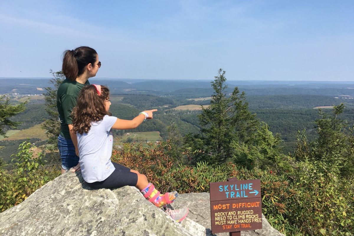 mother daughter duo sitting on a cliff with view
