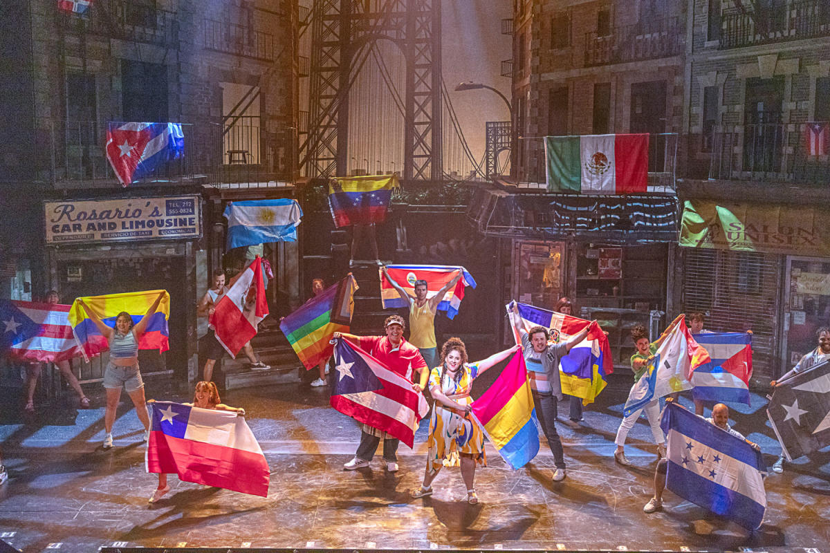 theater artist performing on stage holding various country flags at PA Shakespeare Festival