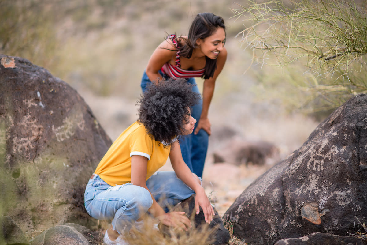 Two women look at petroglyphs etched onto rock