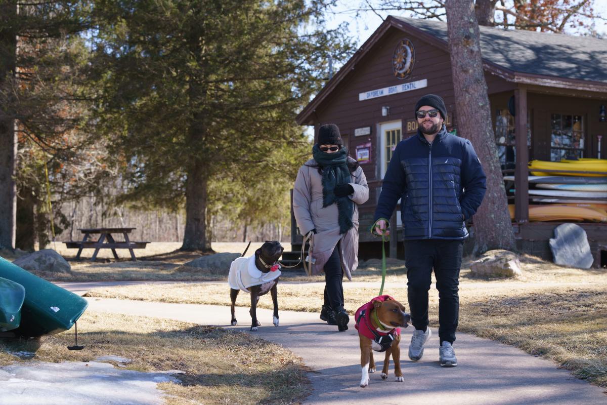 A couple and their dogs walk along a path at Tobyhanna State Park