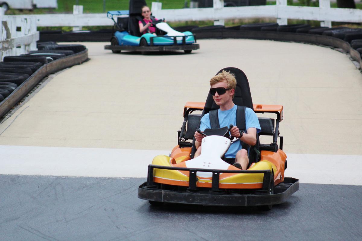 Two teens ride in go-karts on a track.