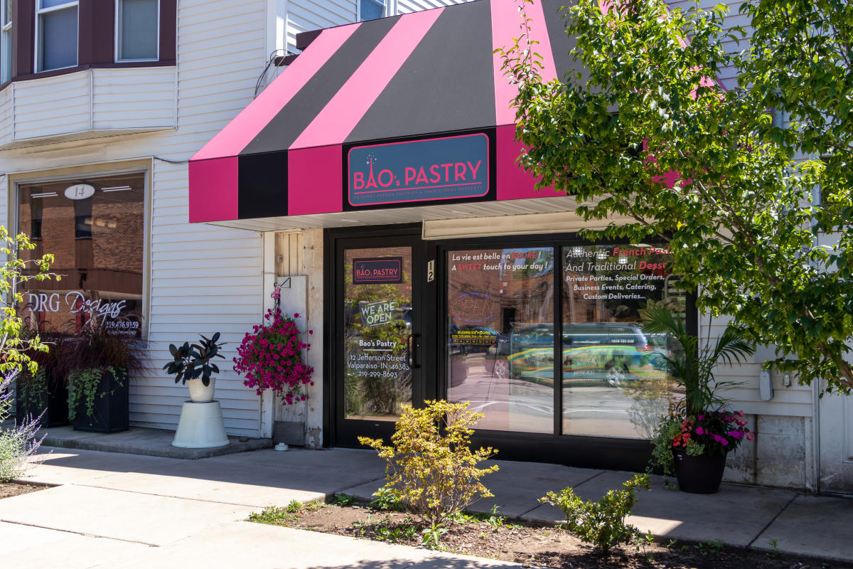 A small bakery has a pink and black awning.