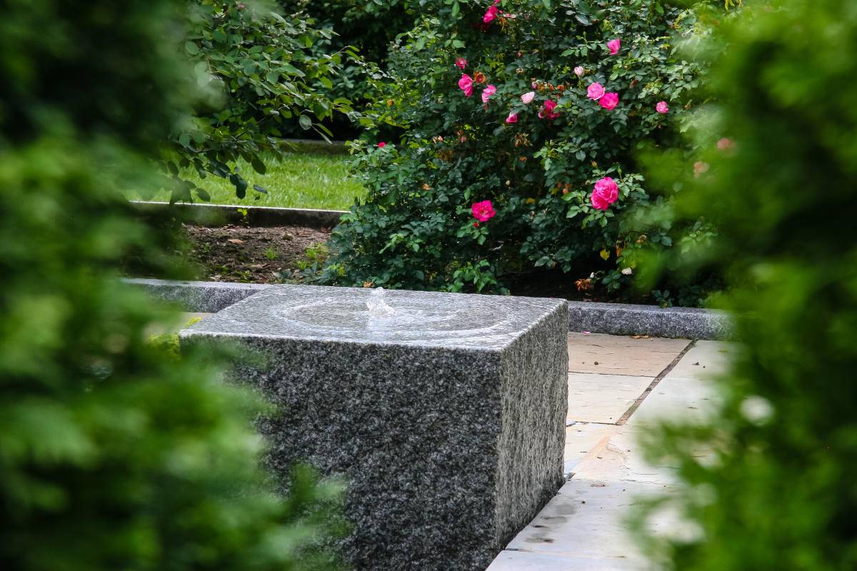 A smooth stone block sits in a garden.