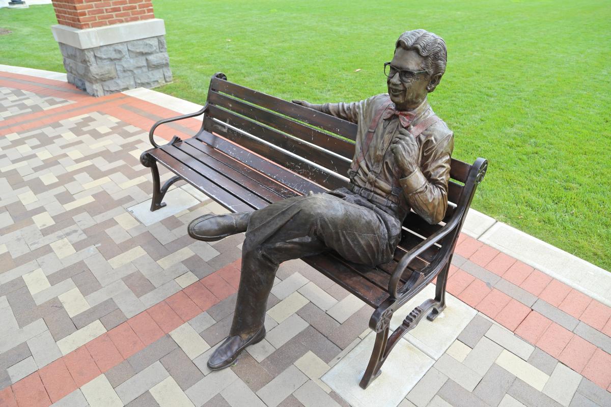 A statue of Orville Redenbacher on a bench.