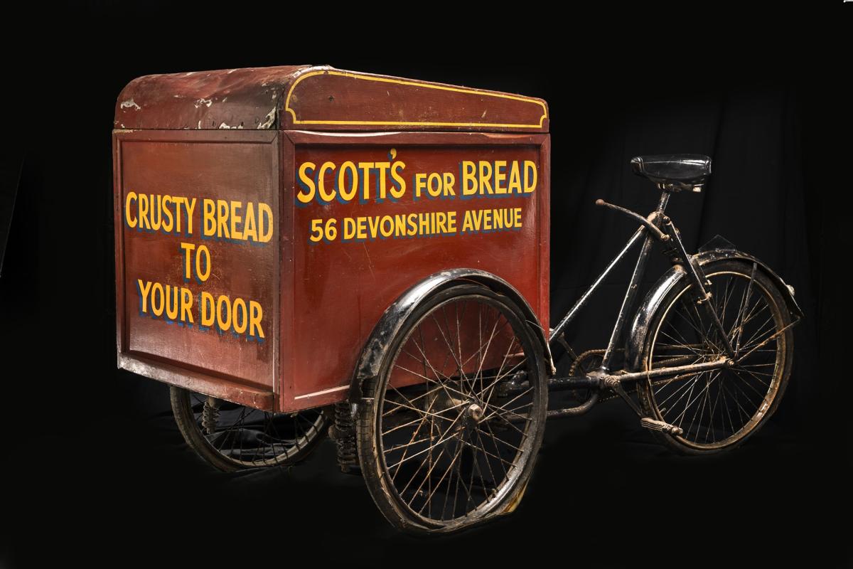 A bike with a box on the front which reads 'crusty bread to your door' on the side it has Scott's for Bread, 56 Devonshire Avenue.