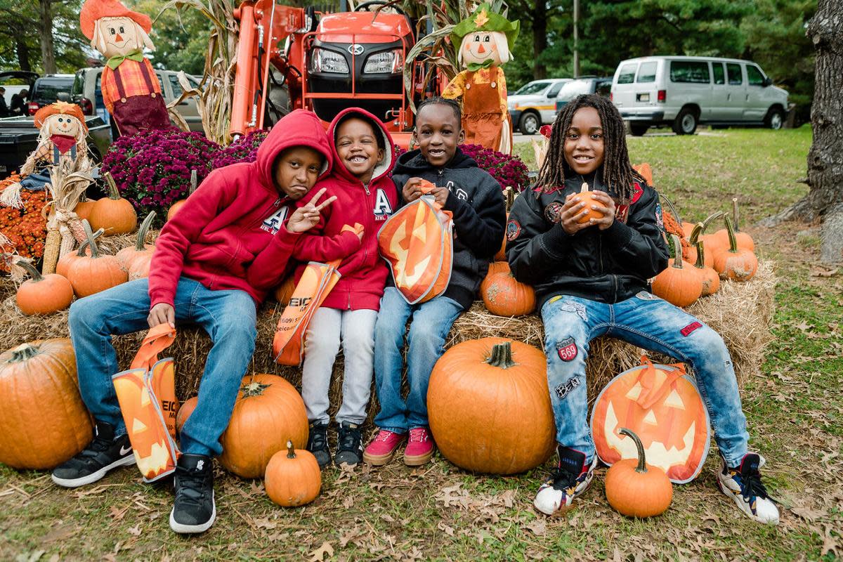 Family of four sitting on pumpkins posing for a picture among fall decor at Hamilton Township's Oktoberfest