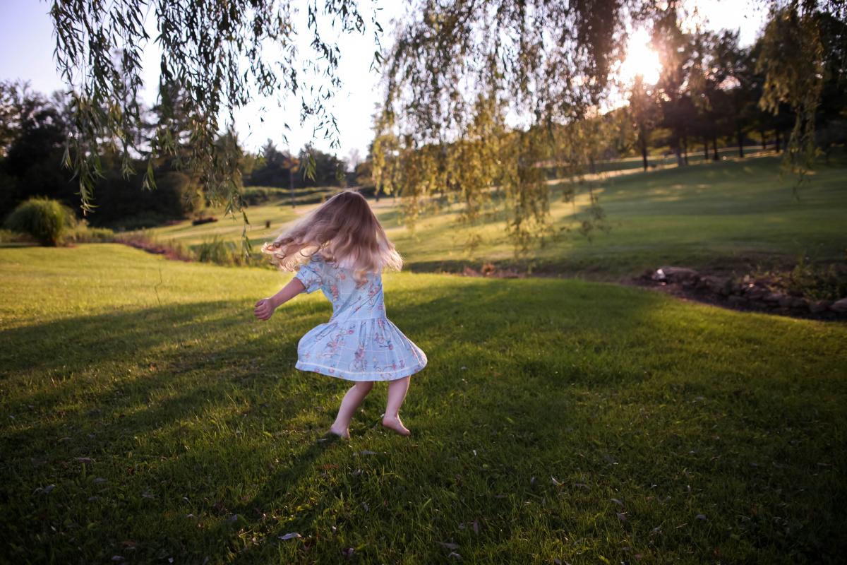 Little girl dancing outside under a tree with Movement for Joy