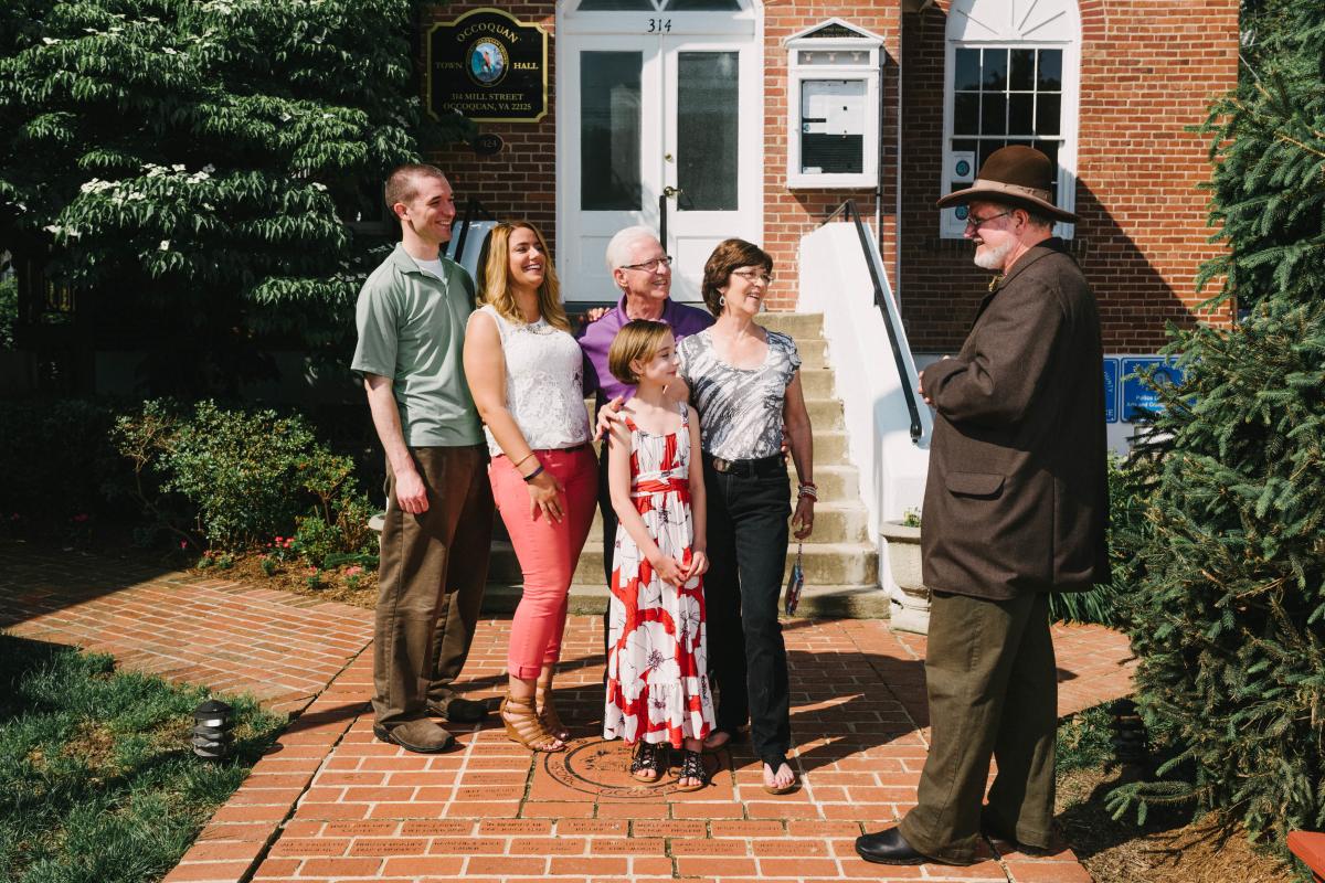 A family standing in front of town hall in Occoquan with a history volunteer