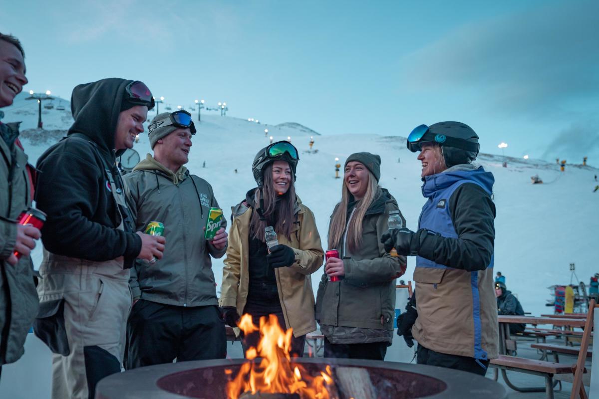 People surrounding a fire during night skiing at Coronet Peak