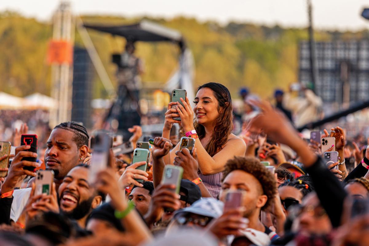 A crowd of people with smartphones taking photos or videos at a music festival.
