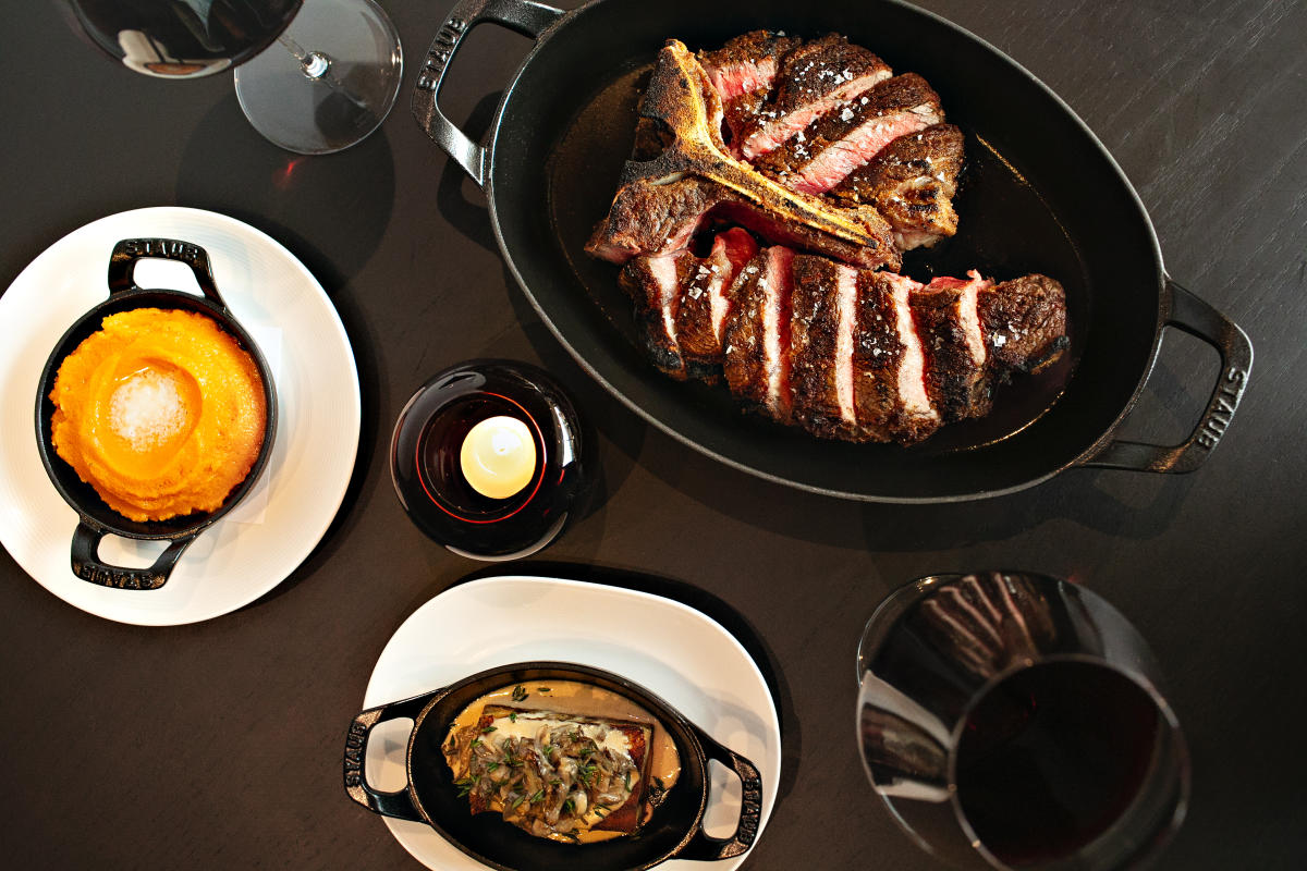 Meat, sides, and wine on a candlelit table at Crawford Brothers Steakhouse