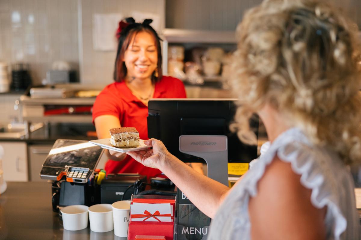 Woman behind the counter working at local lunch spot handing a desert to patron at The Bestro in Rapid City, SD.