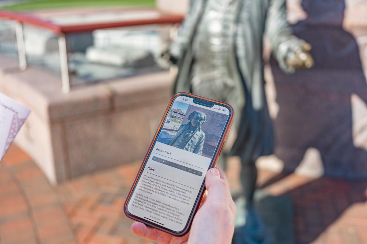 mobile phone looking at the audio tour app with president john adams statue in downtown rapid city