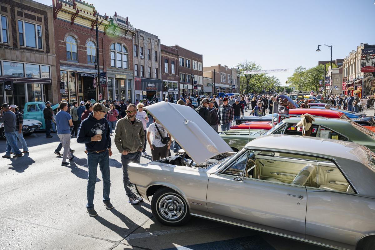 people walking the streets of downtown rapid city touring classic cars during the cruiser car show in rapid city,sd