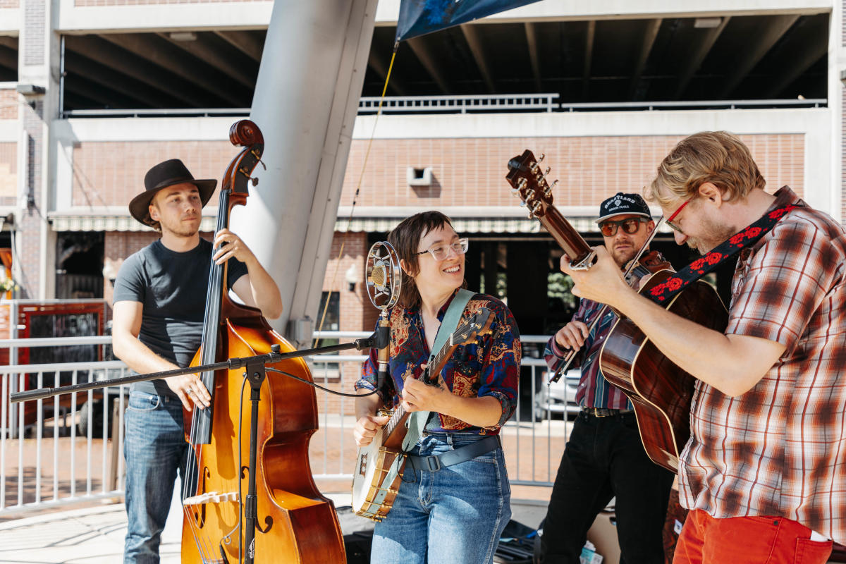 Four person band playing outdoors looking cheerful