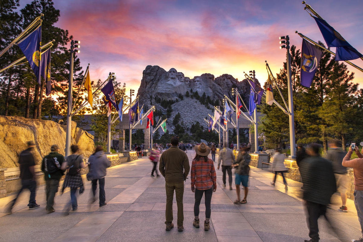 people standing on the avenue of flags at sunset at mount rushmore