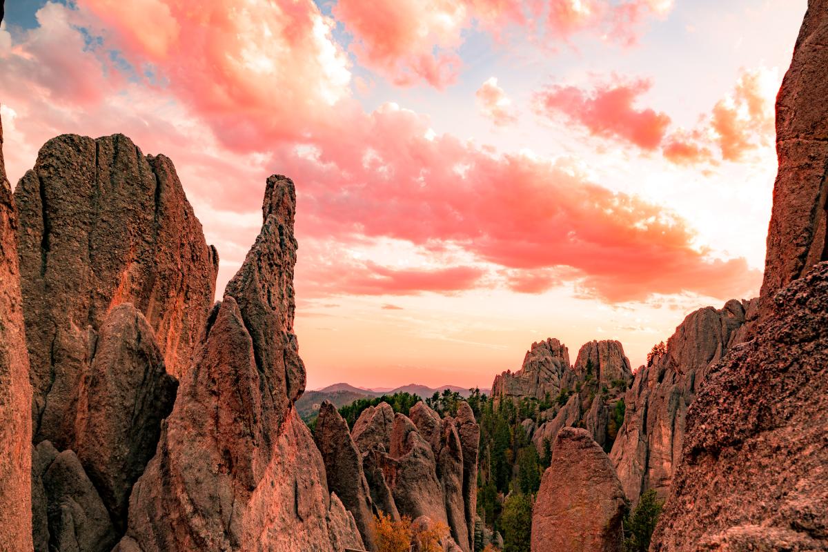 Jagged rock formations under a vibrant pink and orange sunset sky, creating a dramatic and serene landscape. The scene feels majestic and tranquil.