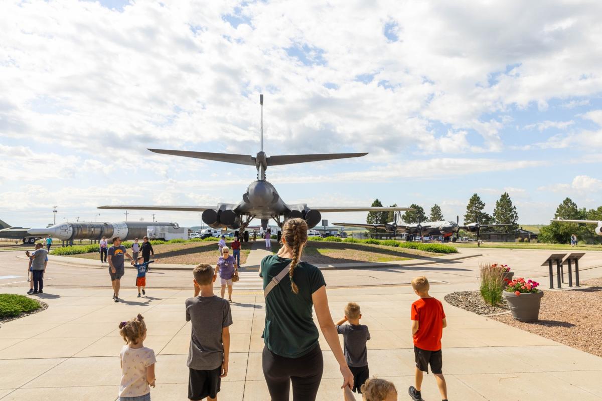 family walking behind the b1 plane on display at the south dakota air and space museum