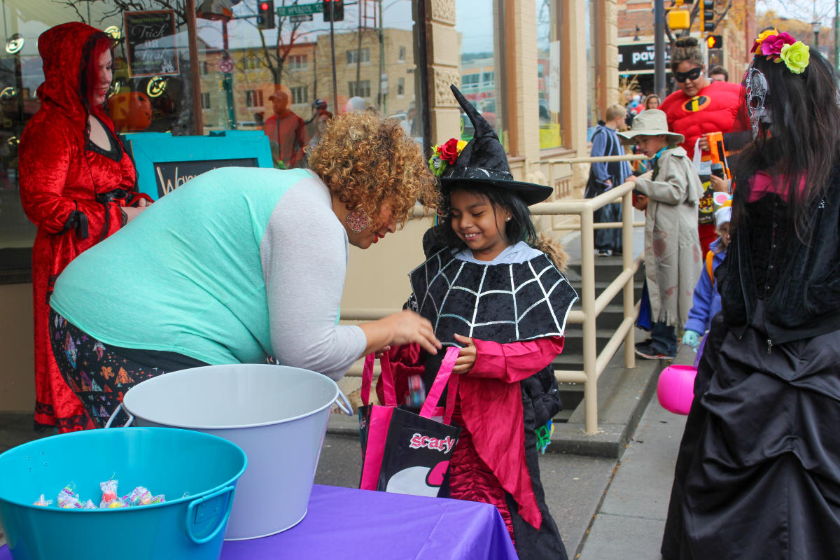 Child dressed in a witch costume collecting candy from a downtown business owner as part of the Downtown Trick-or-Treat event in Rapid City, SD.