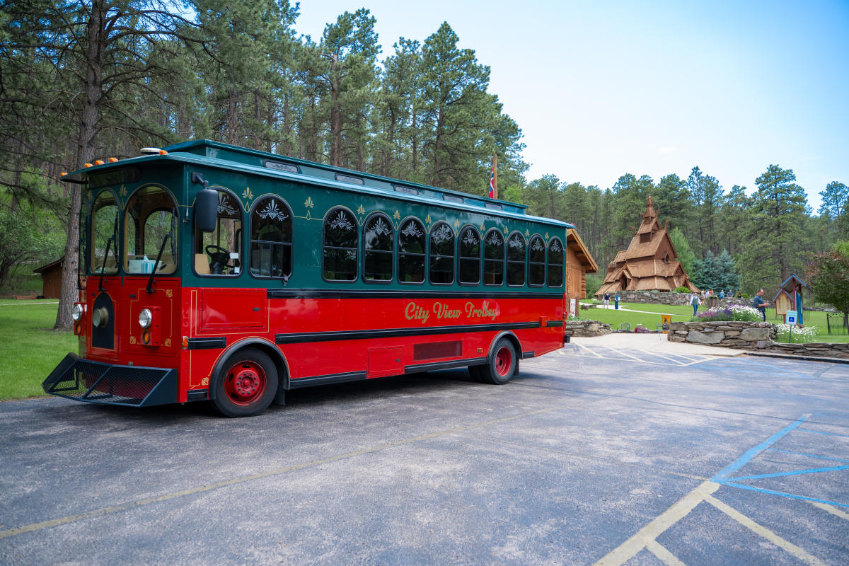 The red City View Trolley sits in the parking lot of the Chapel in the Hills, with the chapel visible in the background.
