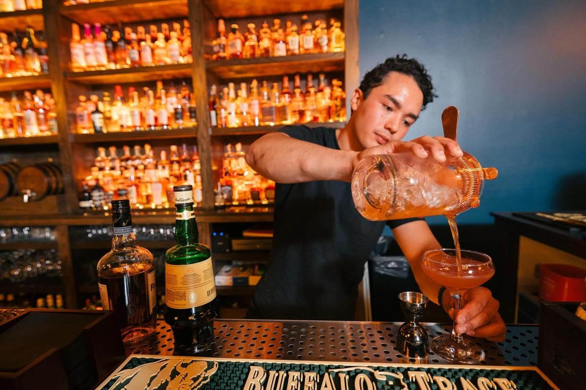 bartender at the windsor block in rapid city pouring a drink with bottles in the background
