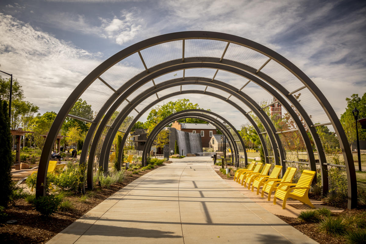 Archways in park with yellow chairs on path