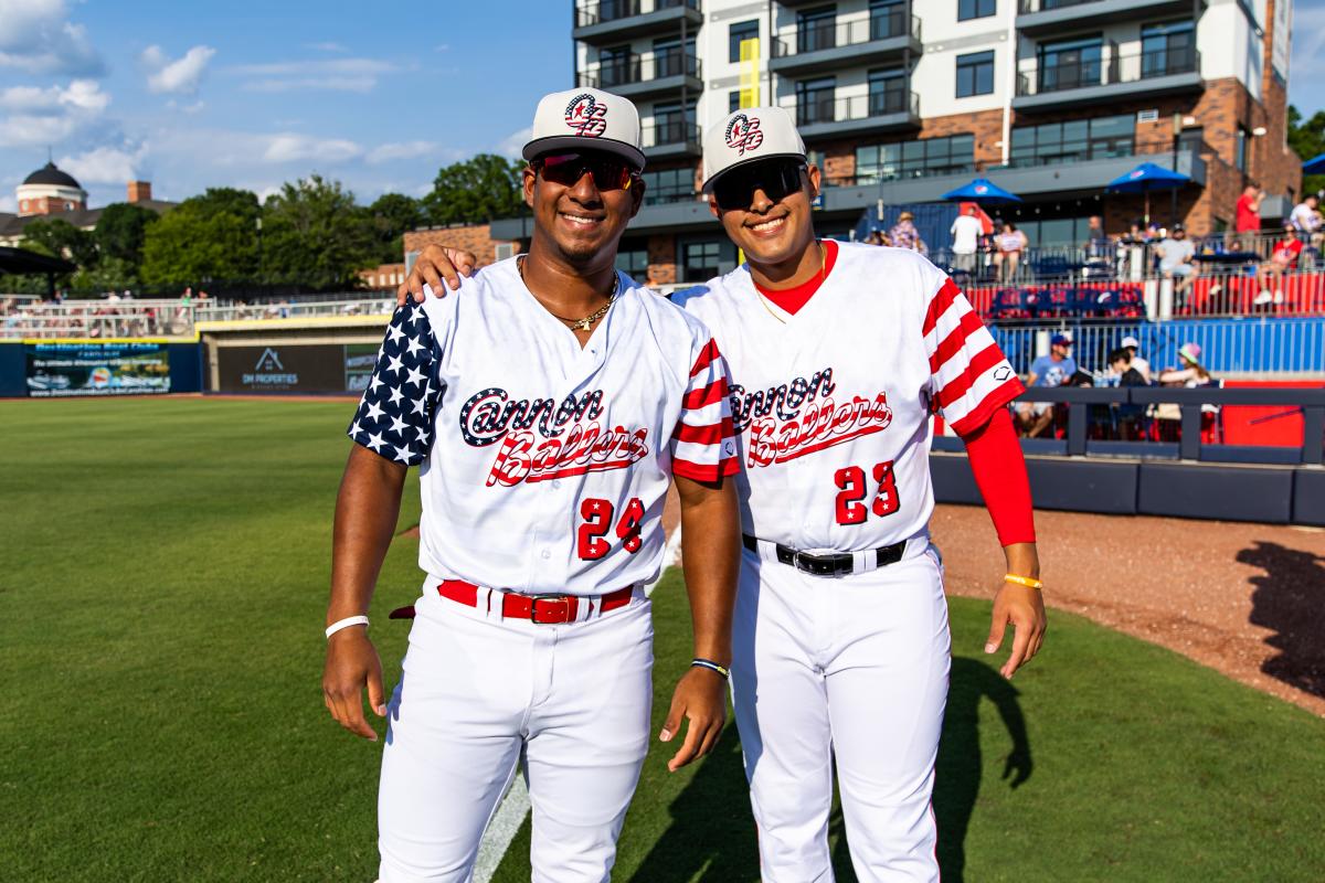 Two baseball players in patriotic uniforms on a ballfield.